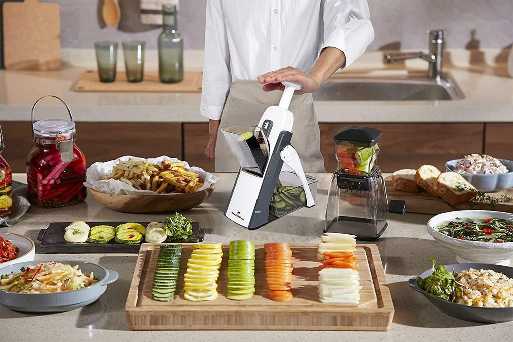 Person using a mandoline slicer to slice vegetables on a kitchen counter.