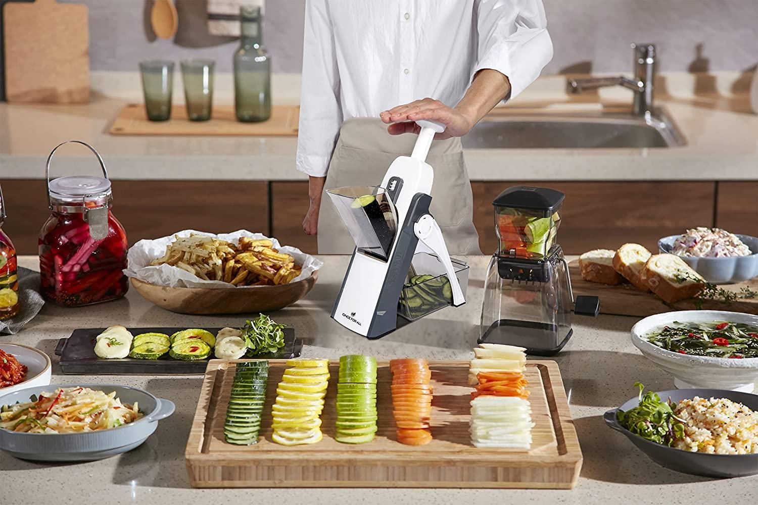 Person using a mandoline slicer to slice vegetables on a kitchen counter.
