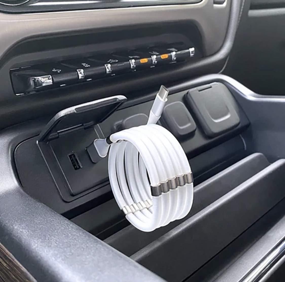 Car cup holder with a white cable organizer holding multiple cables.