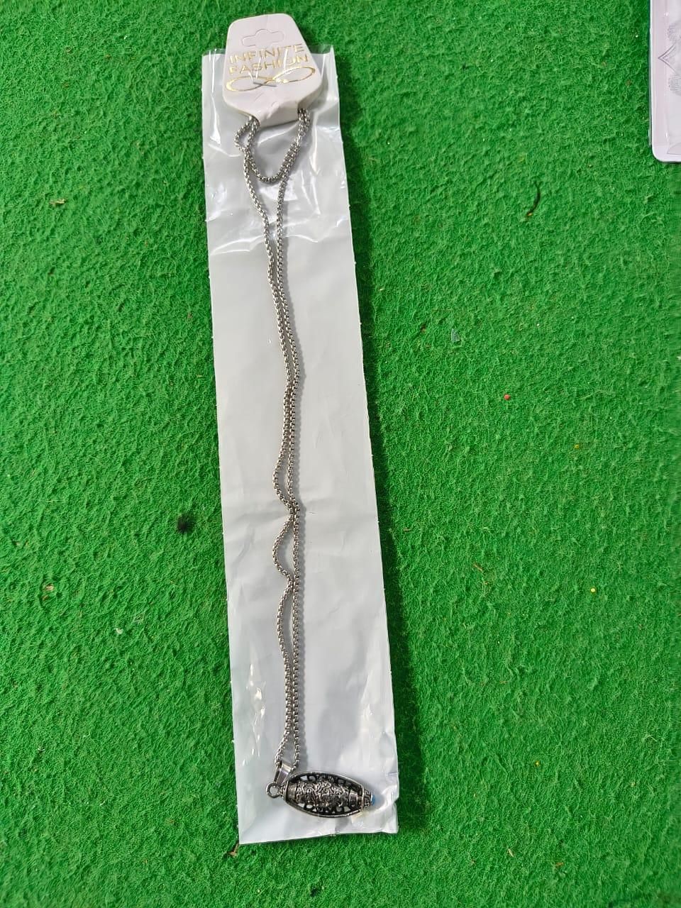 Necklace with a pendant on a clear plastic stand against a green background